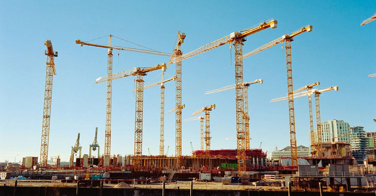 Baustelle mit vielen Baukränen vor blauem Himmel Projektenticklung Brownfield Baurechtschaffung